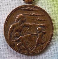 ['air raids defense' commemorative  medal,
  showing a woman sheltering children and bomber planes]