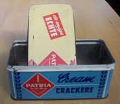 [an old tin box, 'Patria Cream
  Crackers - De Enige Echte']