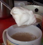 [a spoonful of whipped cream about to be added
  to a cup of coffee]